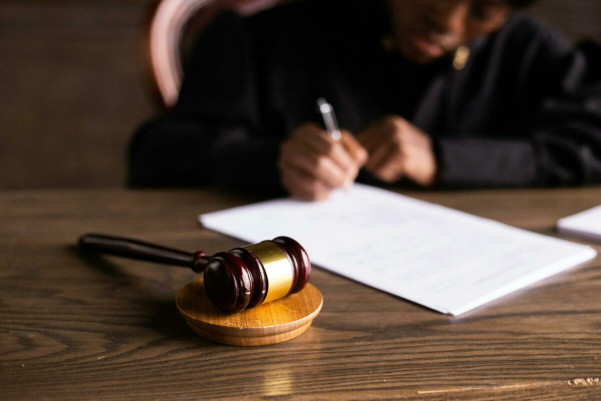 Judge writing on paper on desk, gavel next to it